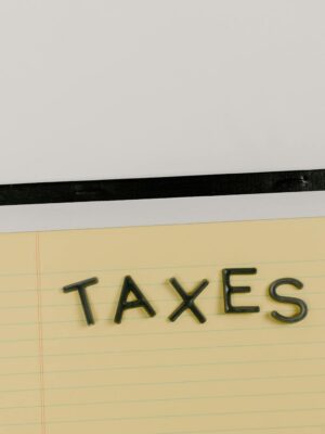 A flat lay of the word 'TAXES' on a yellow notepad, ideal for financial content.